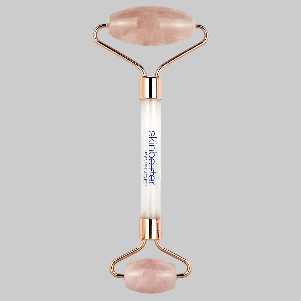 Rose gold and white facial roller with rose quartz stones on a white background