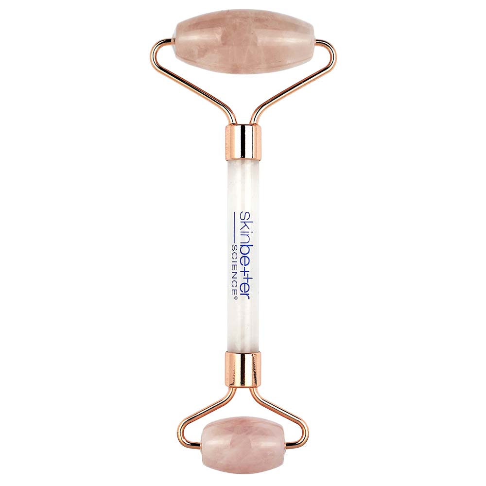 Rose gold and white facial roller with rose quartz stones on a white background