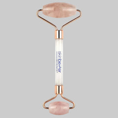 Rose gold and white facial roller with rose quartz stones on a white background