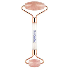 Rose gold and white facial roller with rose quartz stones on a white background